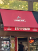 Eine rote Markise über einem Ladengeschäft, auf der das Logo von Astra zu sehen ist, sowie die Aufschrift "Frittebud"
